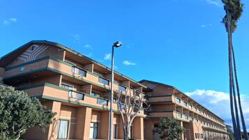 A multi-story hotel with a flat roof, balconies, and a parking lot.