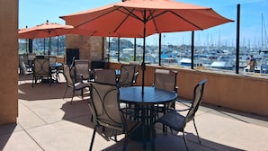 Un patio con mobiliario exterior y vista hacia un puerto deportivo.
