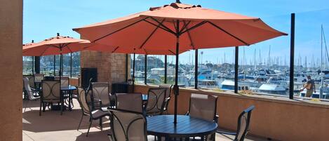 Un patio con mobiliario exterior y vista hacia un puerto deportivo.