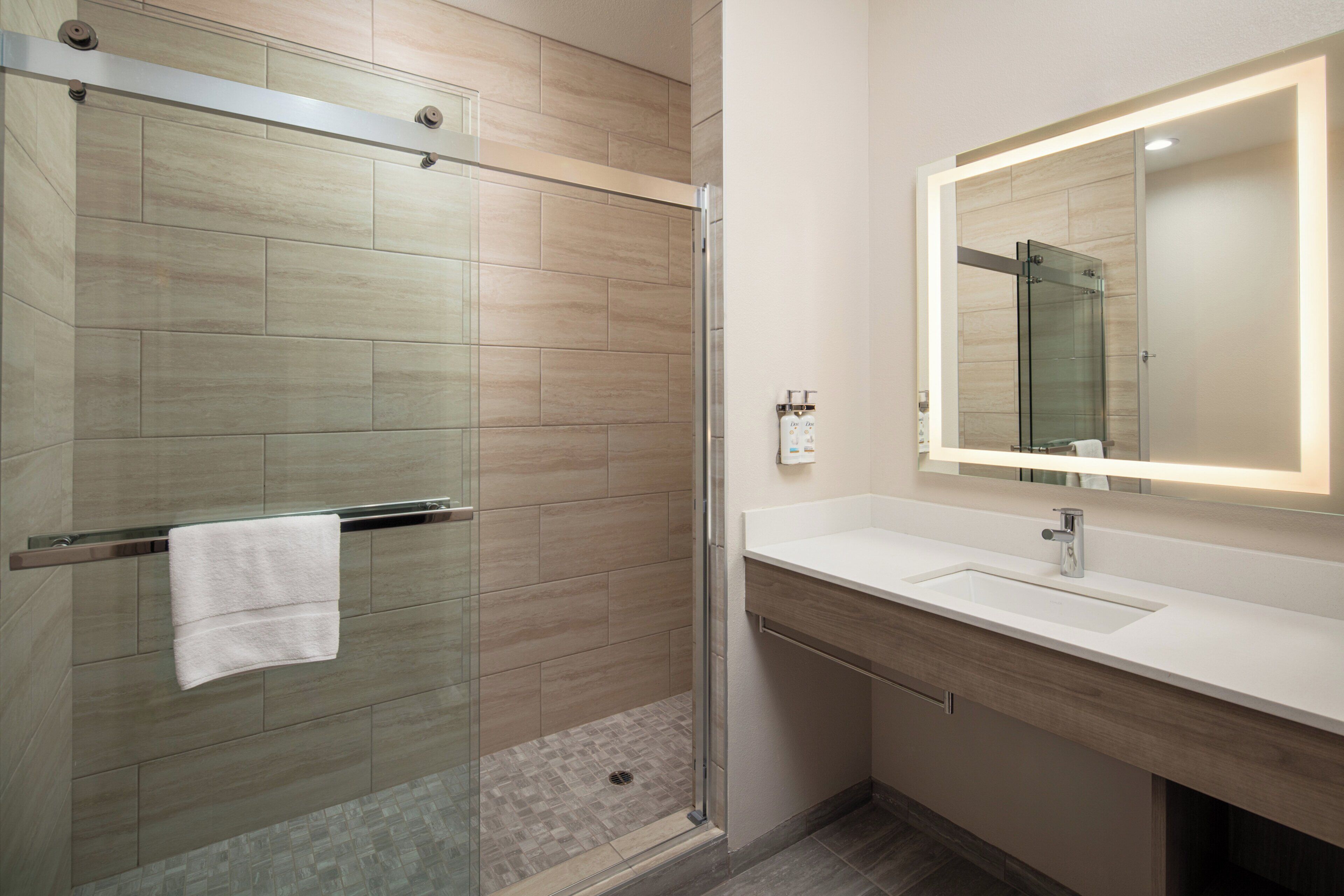 Une salle de bain moderne avec une douche à parois de verre, un lavabo blanc et un grand miroir.