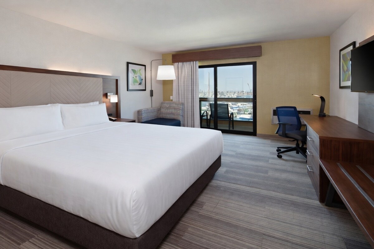 Hotelkamer met een groot bed, een bureau, een stoel, een televisie en uitzicht op de stad.