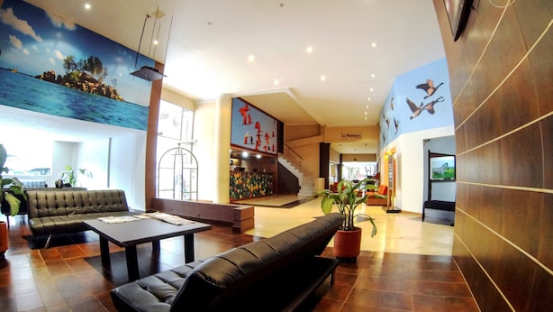 A spacious lobby with a large mural, a staircase, and a seating area with a sofa and coffee table. - Hotel Plaza Rosa (Medellin)