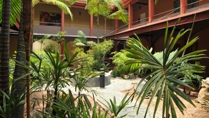 A courtyard with a stone floor, surrounded by various tropical plants and palm trees. - Hotel Plaza Rosa (Medellin)