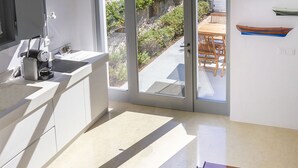 Eine moderne Küche mit großem Fenster, einem Essbereich mit Holzmöbeln und Blick auf einen Garten.