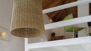 Ein modernes Interieur mit einer Holztreppe, einer gewebten Pendelleuchte und einem Bücherregal mit Büchern und Dekoration.