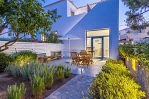 A modern house with a patio, outdoor seating, and a well-maintained garden.