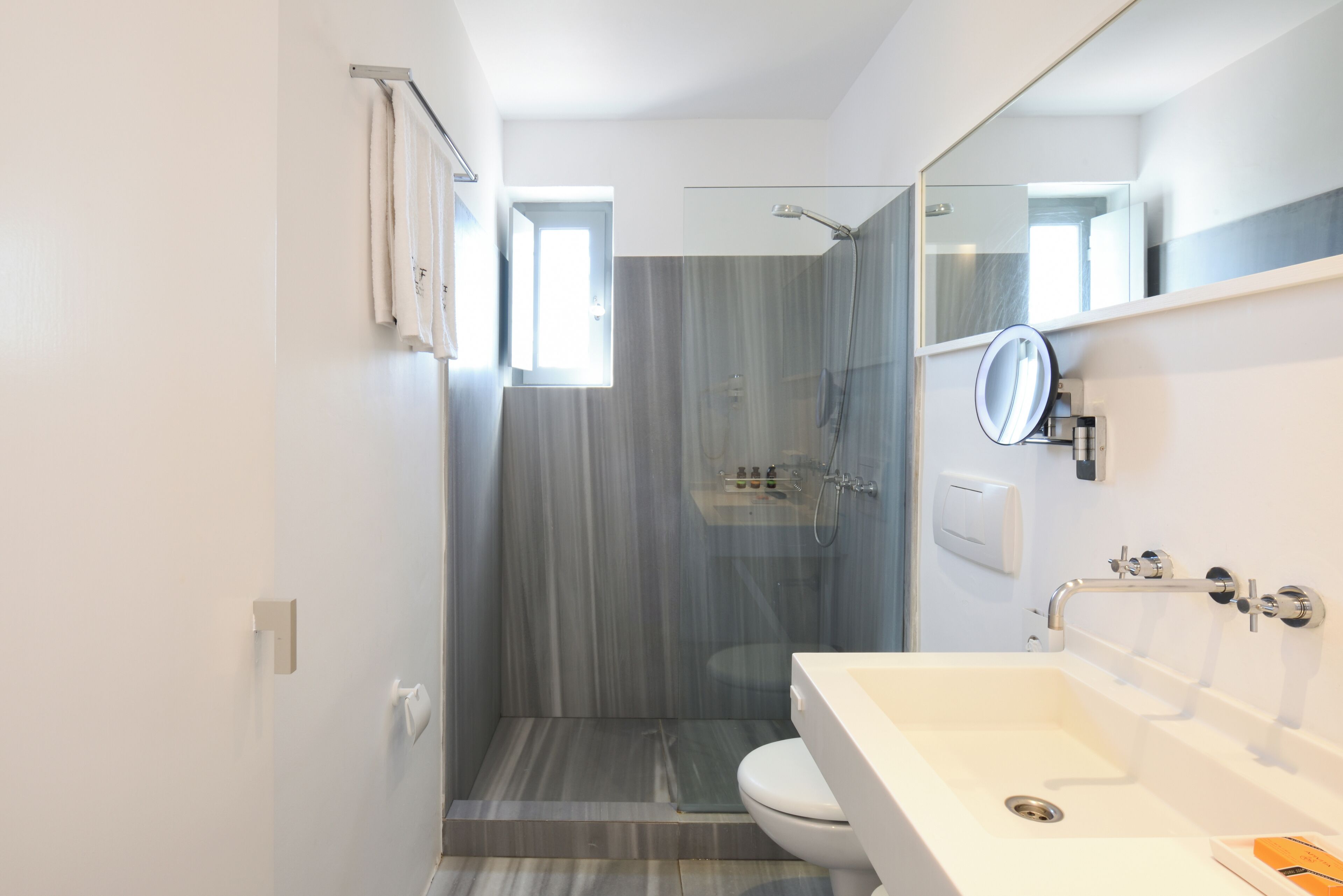 A modern bathroom with a shower, toilet, and sink.
