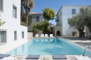 Una piscina al aire libre, sombrillas, sillones reclinables de piscina