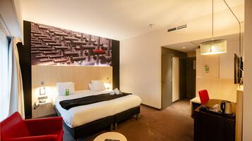 A hotel room with a bed, a desk, a chair, a small table, and a wall with a unique design.