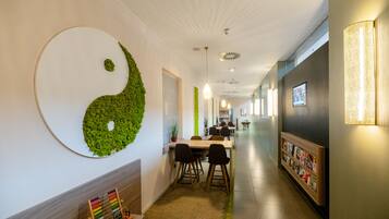 Un pasillo con un gran símbolo yin-yang en la pared, una recepción y una estantería con revistas.