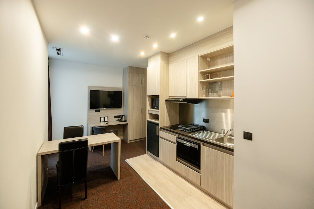 A compact kitchen with a dining area, built-in appliances, and a flat-screen TV.