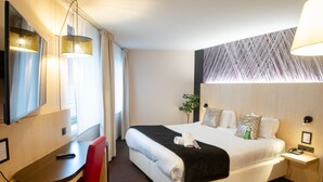 Una habitación de hotel con una cama, un escritorio, una silla, una lámpara y un espejo.