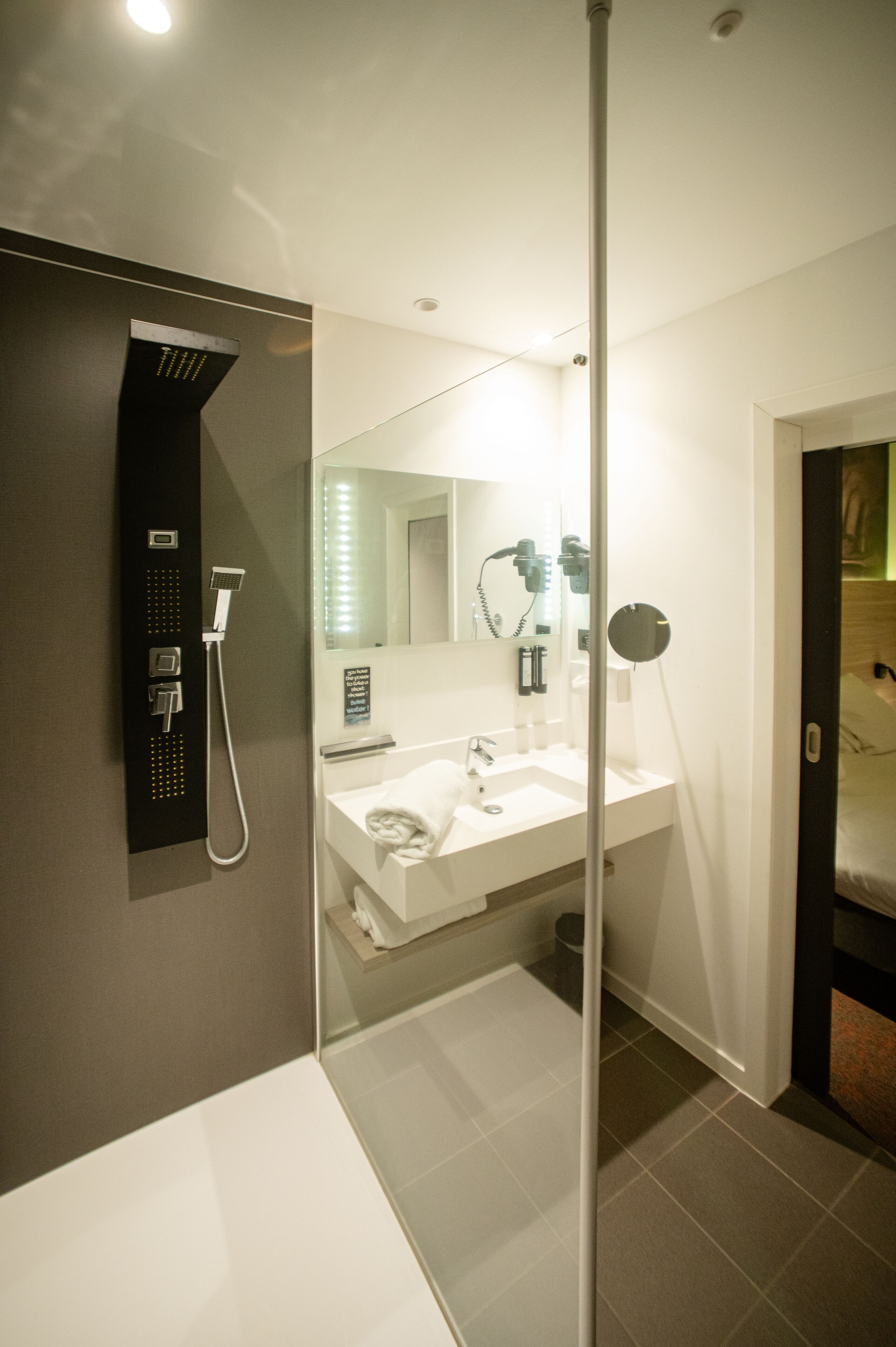 A modern bathroom with a shower, sink, and mirror.