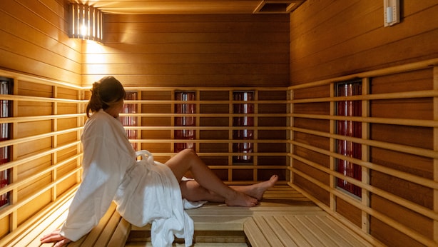 Una sauna con bancos de madera y estantes llenos de botellas.