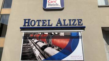 Letrero del Hotel Alize con un cartel que anuncia Mouscron como la ciudad textil.