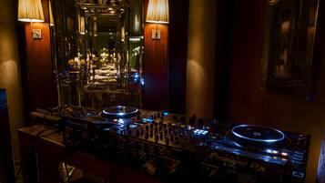A DJ setup with Pioneer DJ equipment, two wall-mounted lamps, and a mirror reflecting the room.