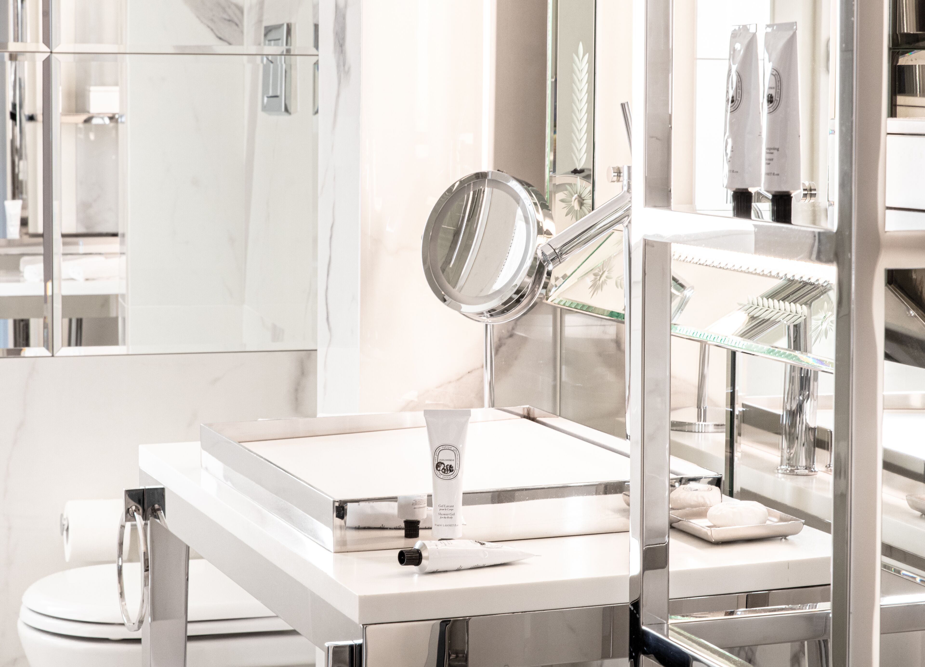 Un baño moderno con lavabo blanco, espejo y cabina de ducha con mampara de vidrio.