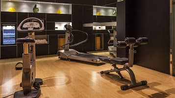 Un gimnasio con máquinas de cardio, un espejo grande y una máquina expendedora.