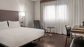 Una habitación de hotel moderna con una cama grande, un escritorio, una silla y una mesita.