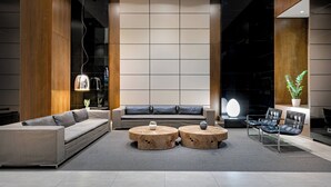 A modern living room with a sofa, two round wooden tables, and a coffee table. - AC Hotel Porto by Marriott (Porto)