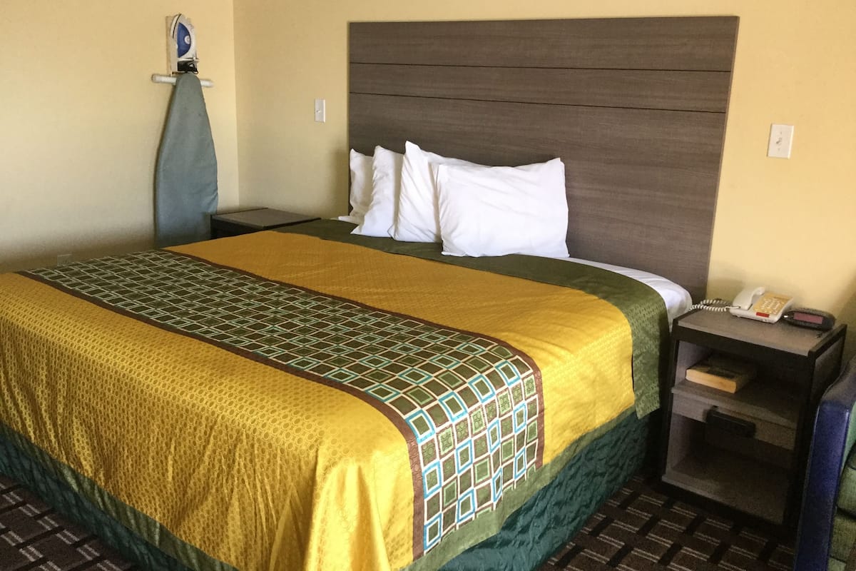 Une chambre d’hôtel équipée d’un lit, d’une table de chevet, d’un téléphone et d’un fer à repasser fixé au mur.