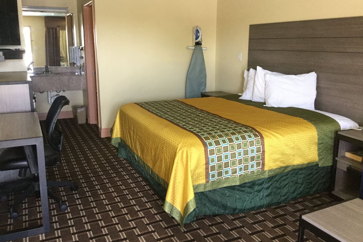 Une chambre d’hôtel avec un lit, un bureau, une chaise et un miroir.