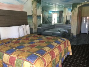 Une chambre d’hôtel avec un grand lit, une baignoire et une vue sur la mer, grâce à une grande fenêtre.