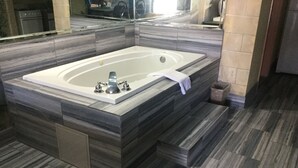 Une salle de bain moderne dotée d’une grande baignoire sur pieds, d’un revêtement de sol imitant le marbre et d’une cabine de douche en verre.