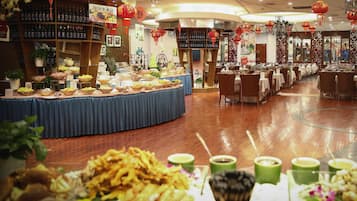 Restaurante com buffet, mesas e cadeiras.