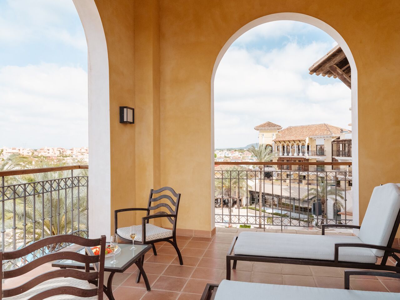 A balcony with a table, chairs, and a view of buildings.