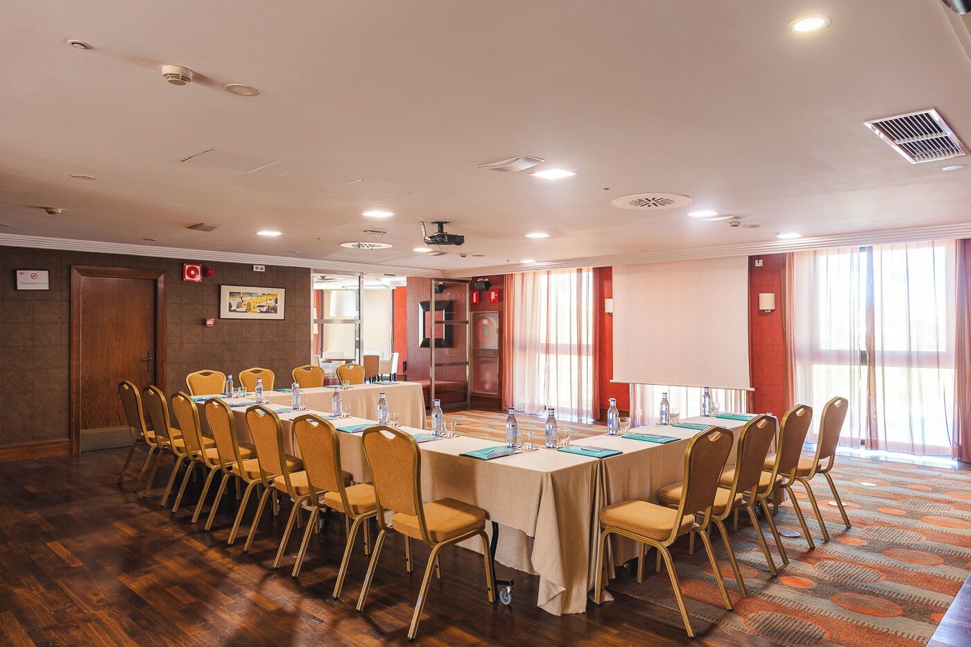Une salle de conférence équipée d’une longue table, de chaises et d’un écran de projection.