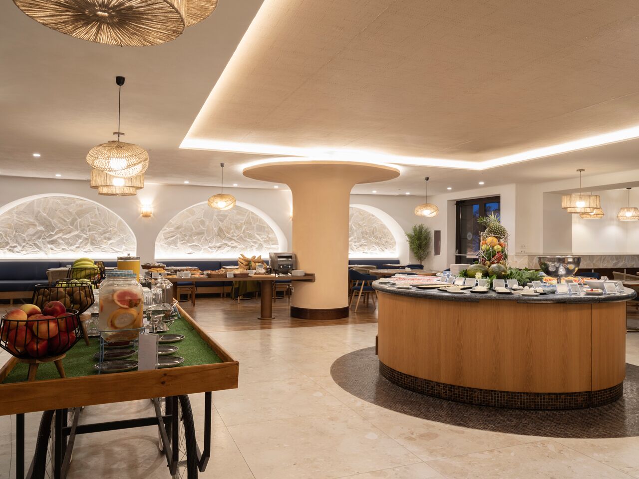 Un hall d’hôtel moderne doté d’un îlot central, de coins salon et de grandes fenêtres.