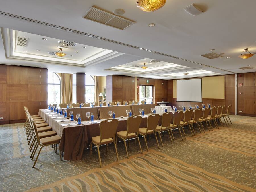 A conference room with a long table, chairs, and a projector screen.