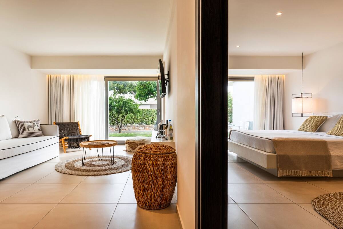 Une chambre d’hôtel moderne équipée d’un canapé, d’un lit, d’une table à manger et d’une grande fenêtre.