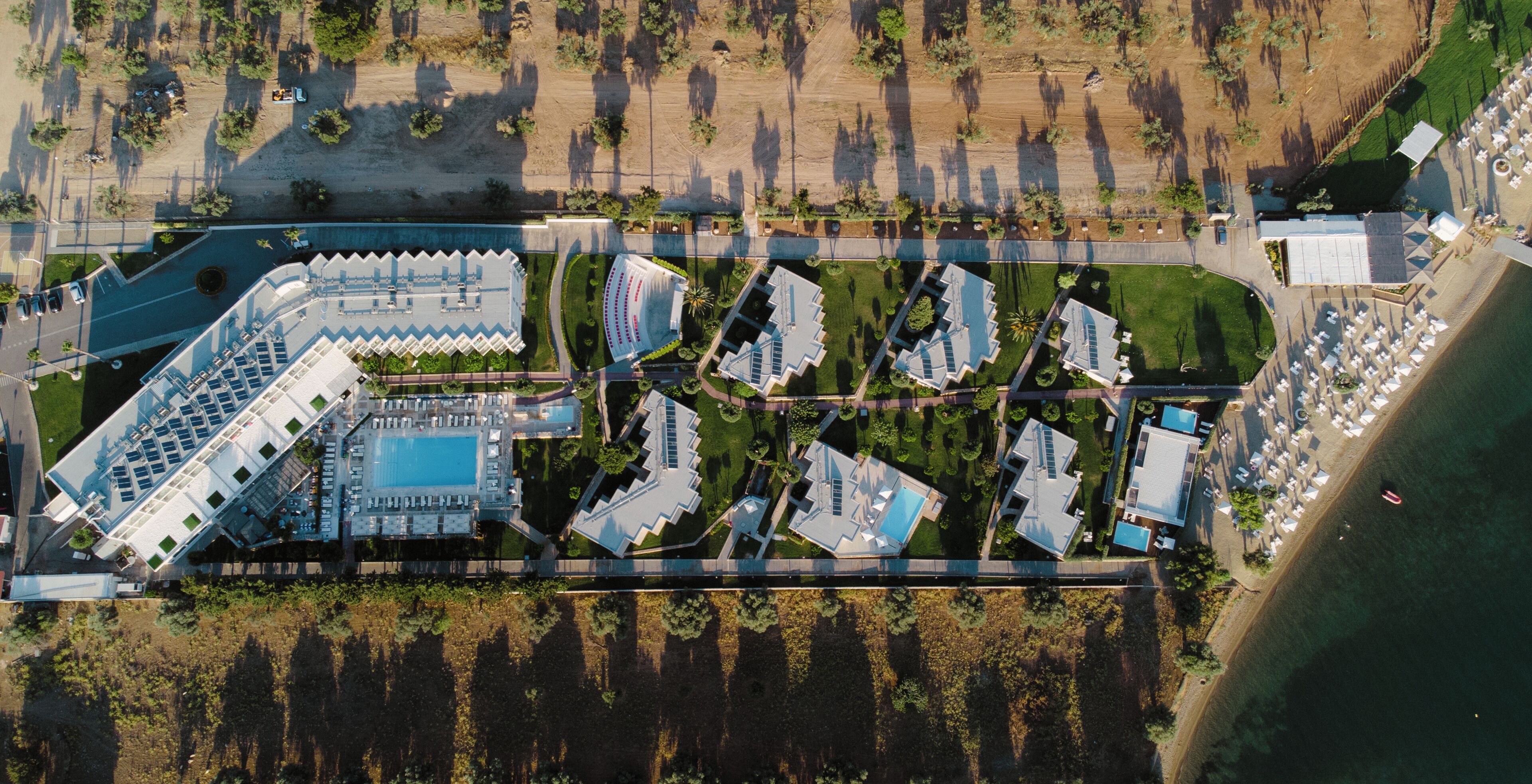 Luchtbeeld van een resort met meerdere gebouwen, een zwembad en een strandgebied.