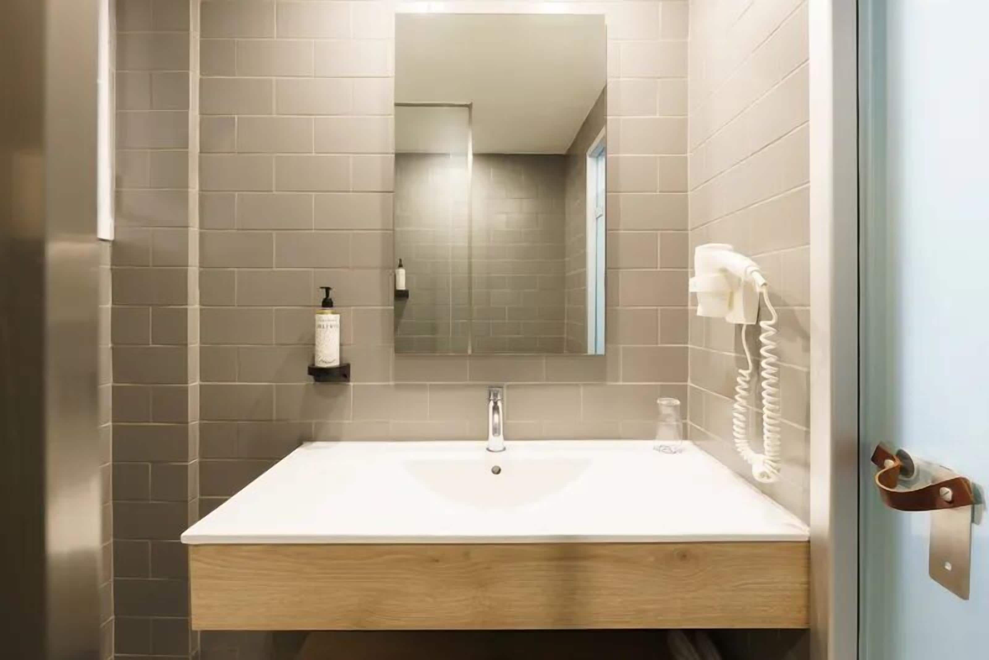 A modern bathroom with a white sink, a mirror, and a towel rack.