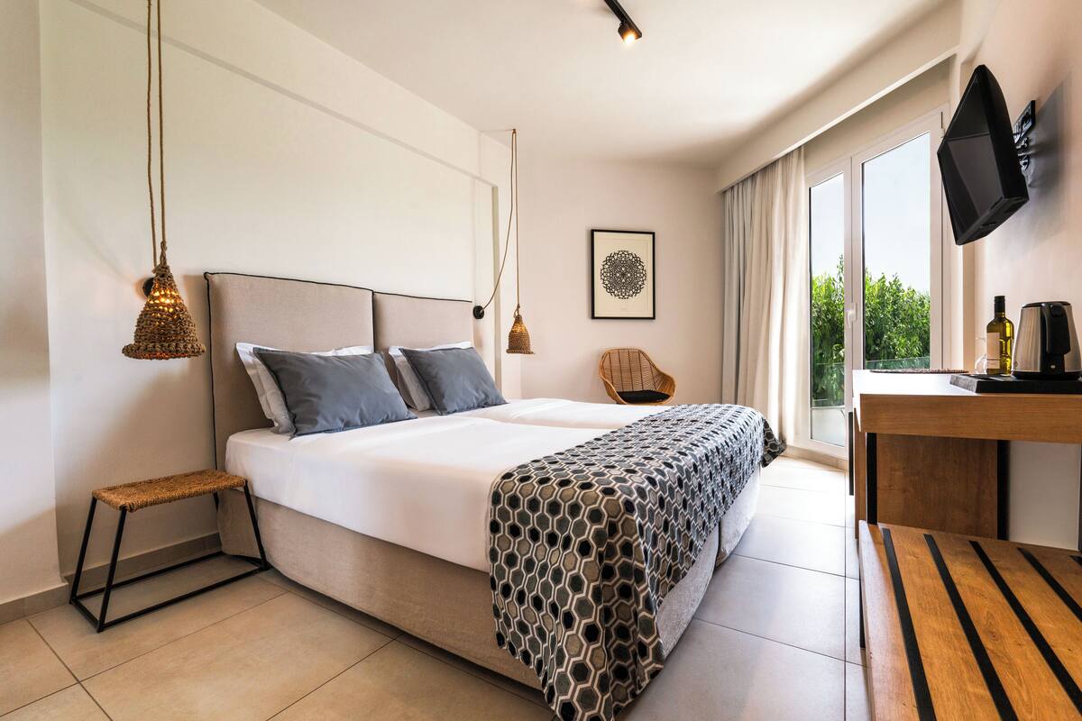 A modern bedroom with a large bed, bedside tables, a chair, a desk, and a TV.
