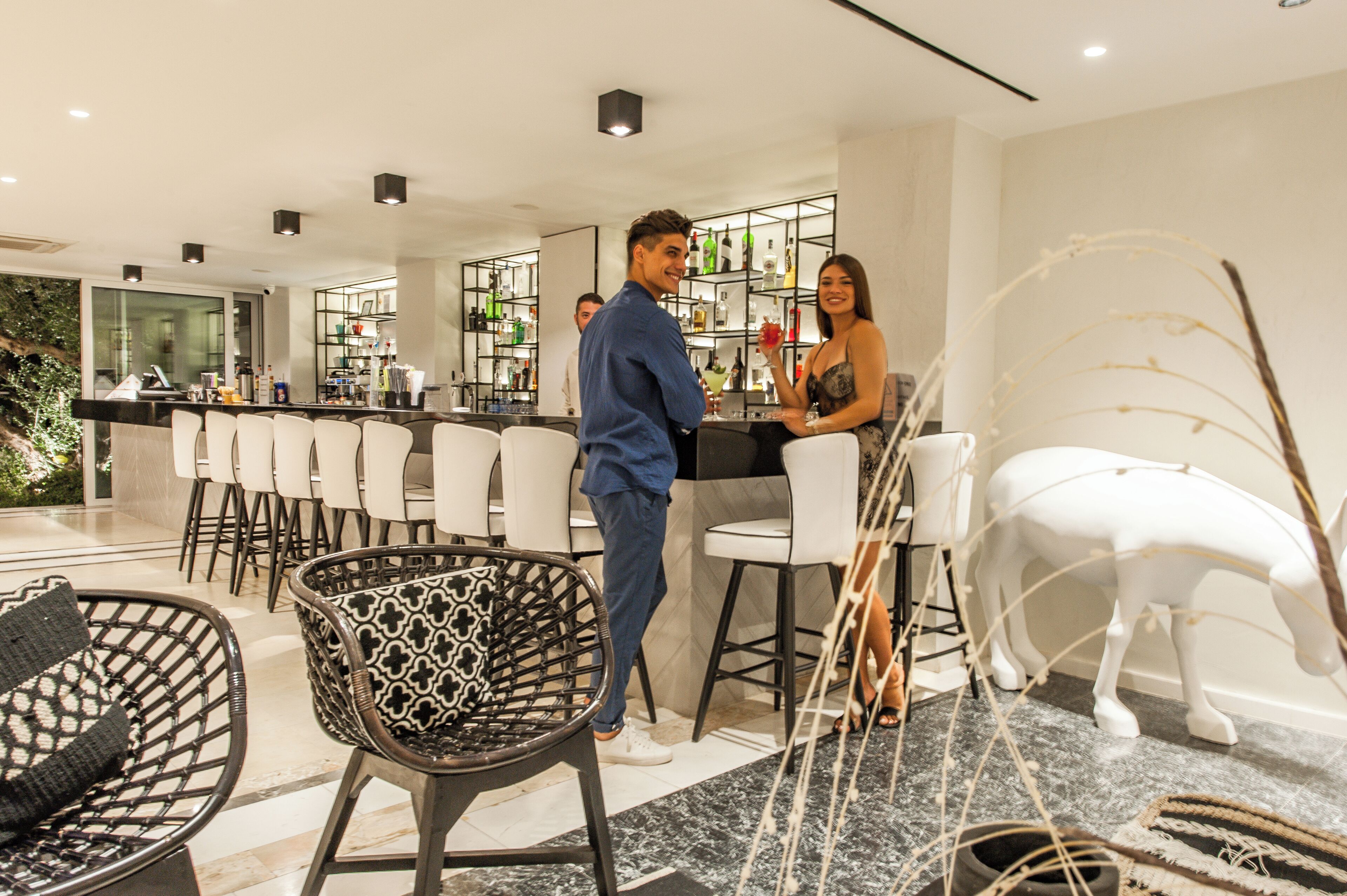 A modern bar area with a counter, seating, and a decorative white horse statue.