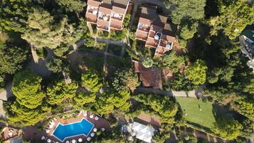 Vista aerea di una zona residenziale con diverse case, una piscina e un prato curato.