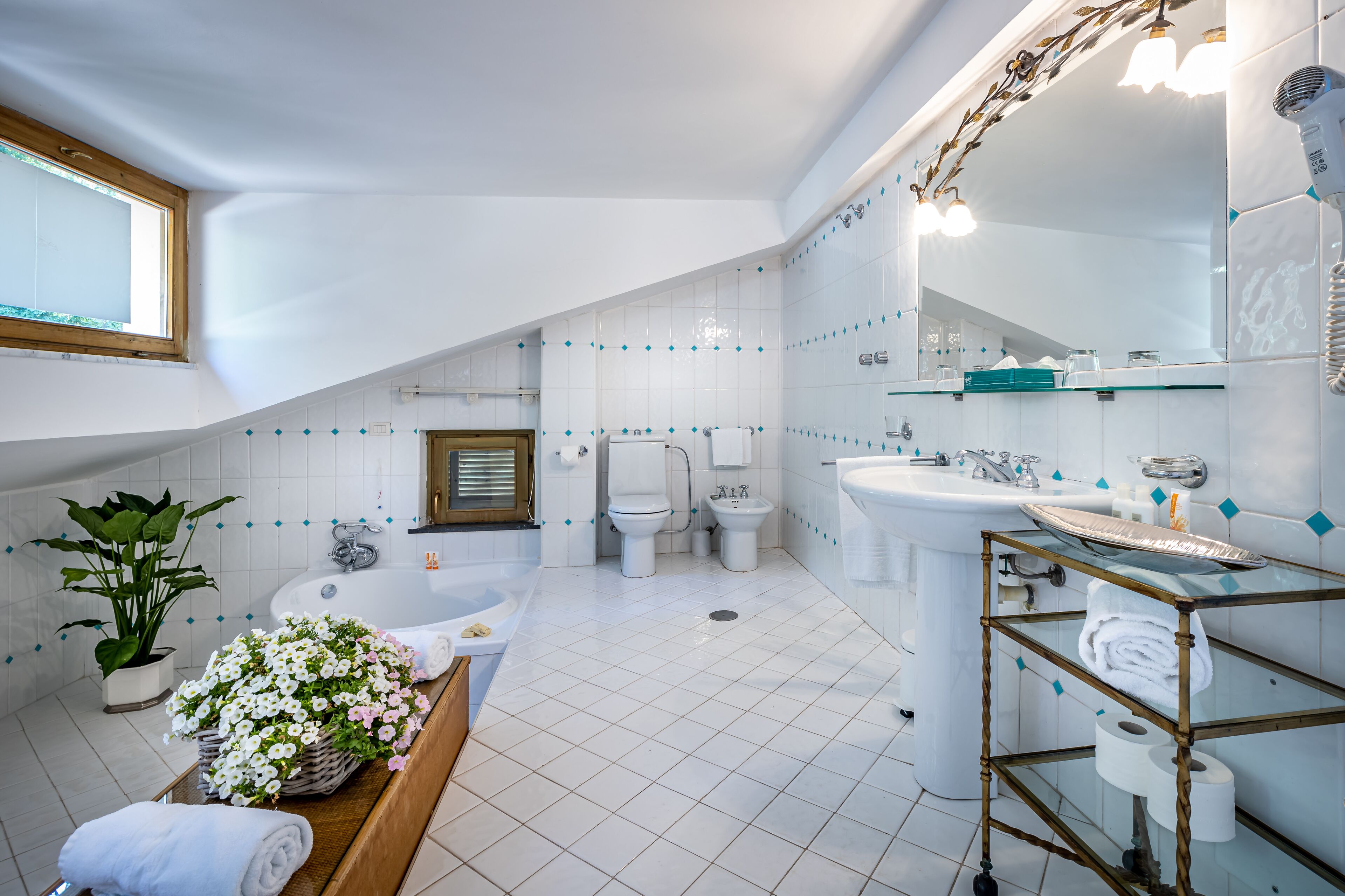 A modern bathroom with a large bathtub, a separate shower area, and a vanity with a glass shelf.