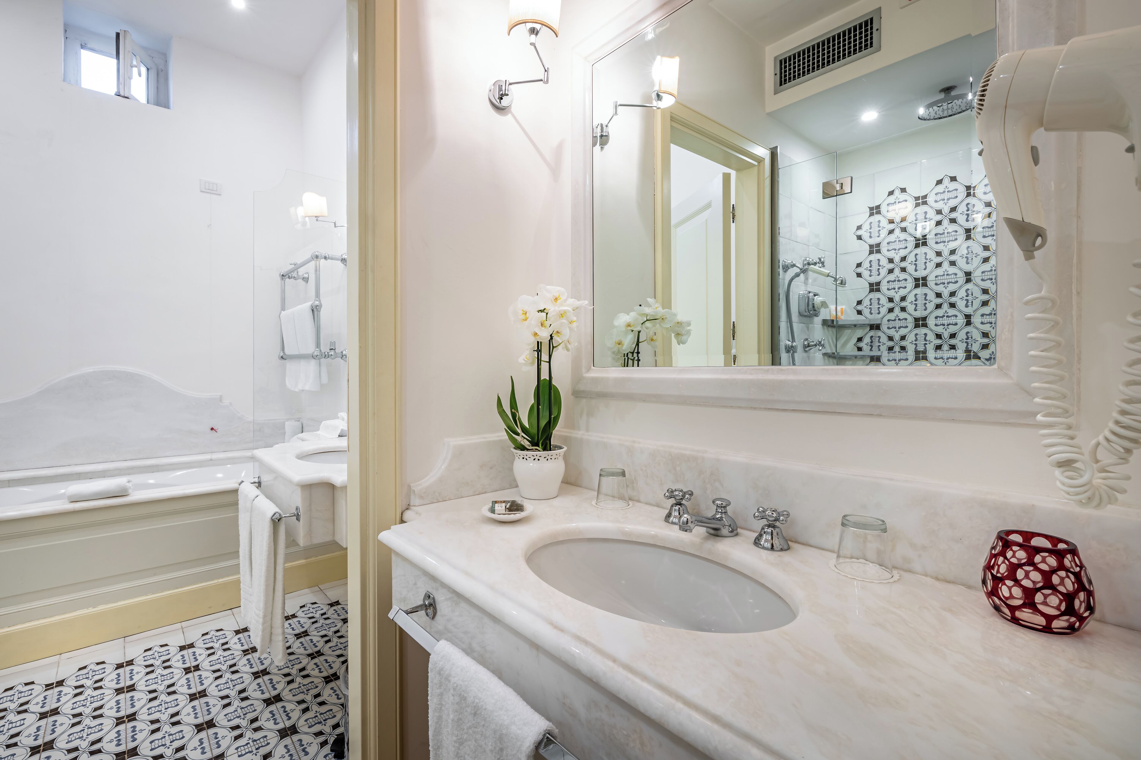 A bathroom with a bathtub, a sink, a mirror, and a potted plant.