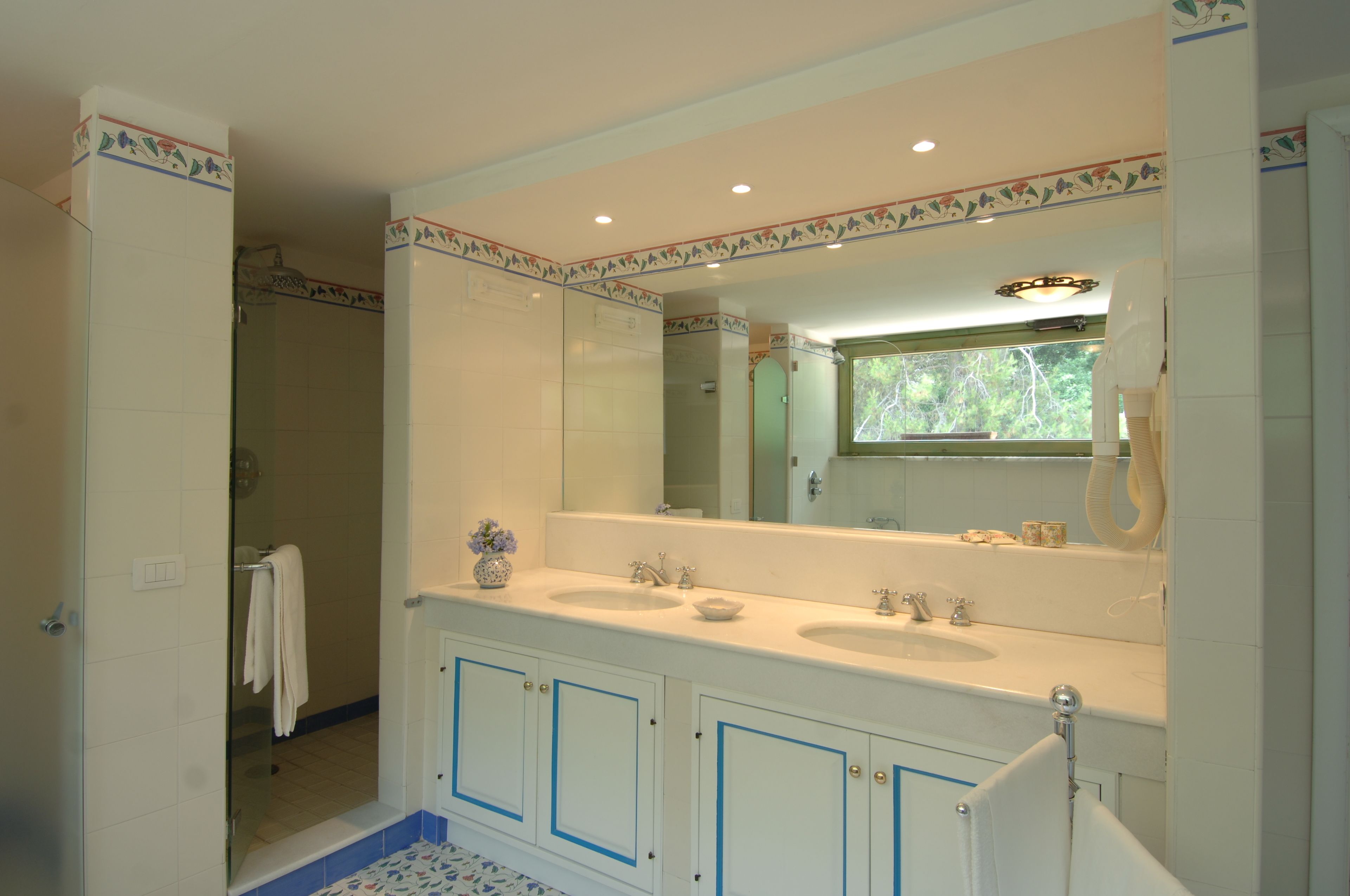 A bathroom with two sinks, a large mirror, and a shower.
