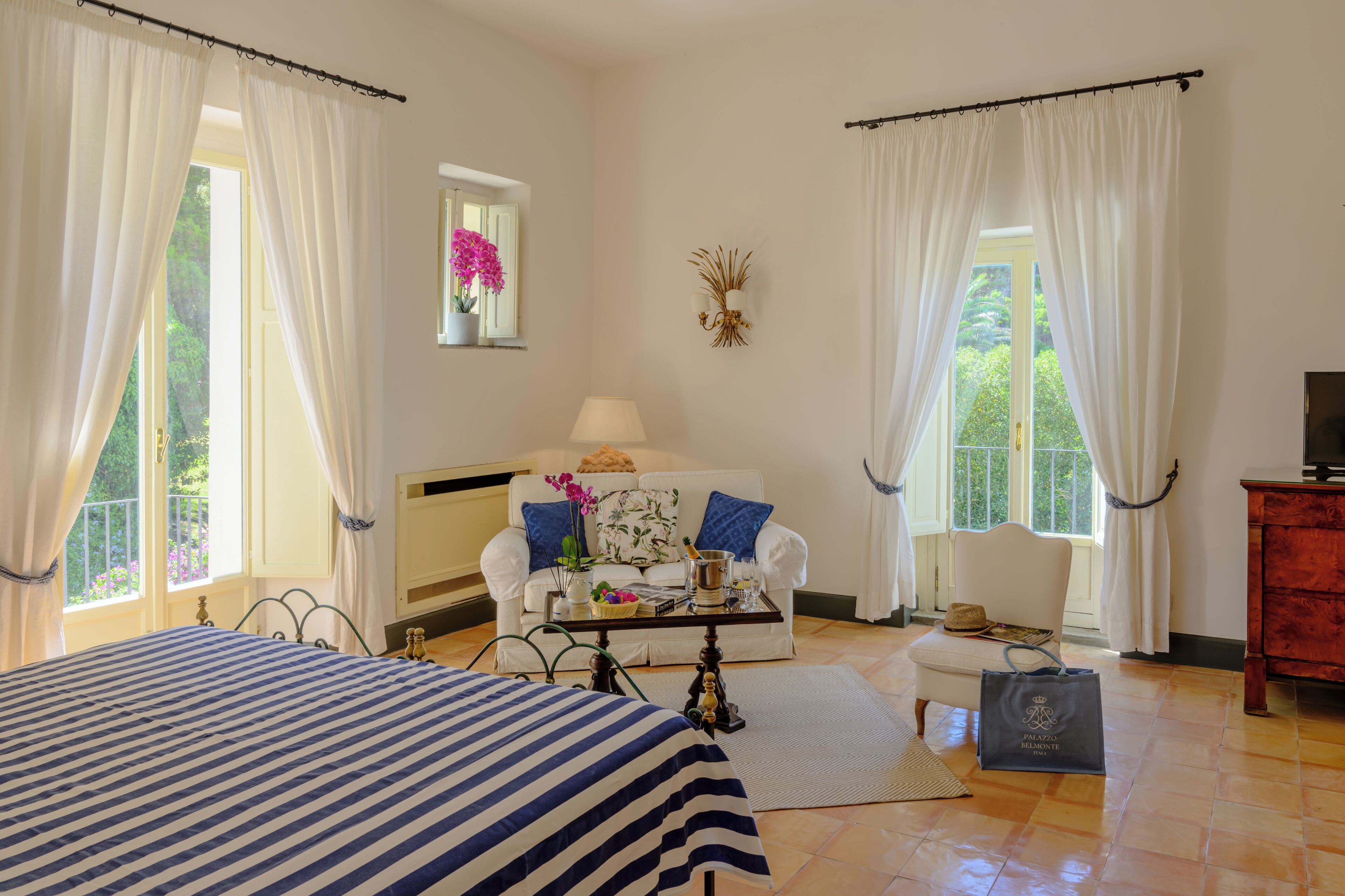 A hotel room with a bed, a sofa, a small table, a TV, and a window with curtains.