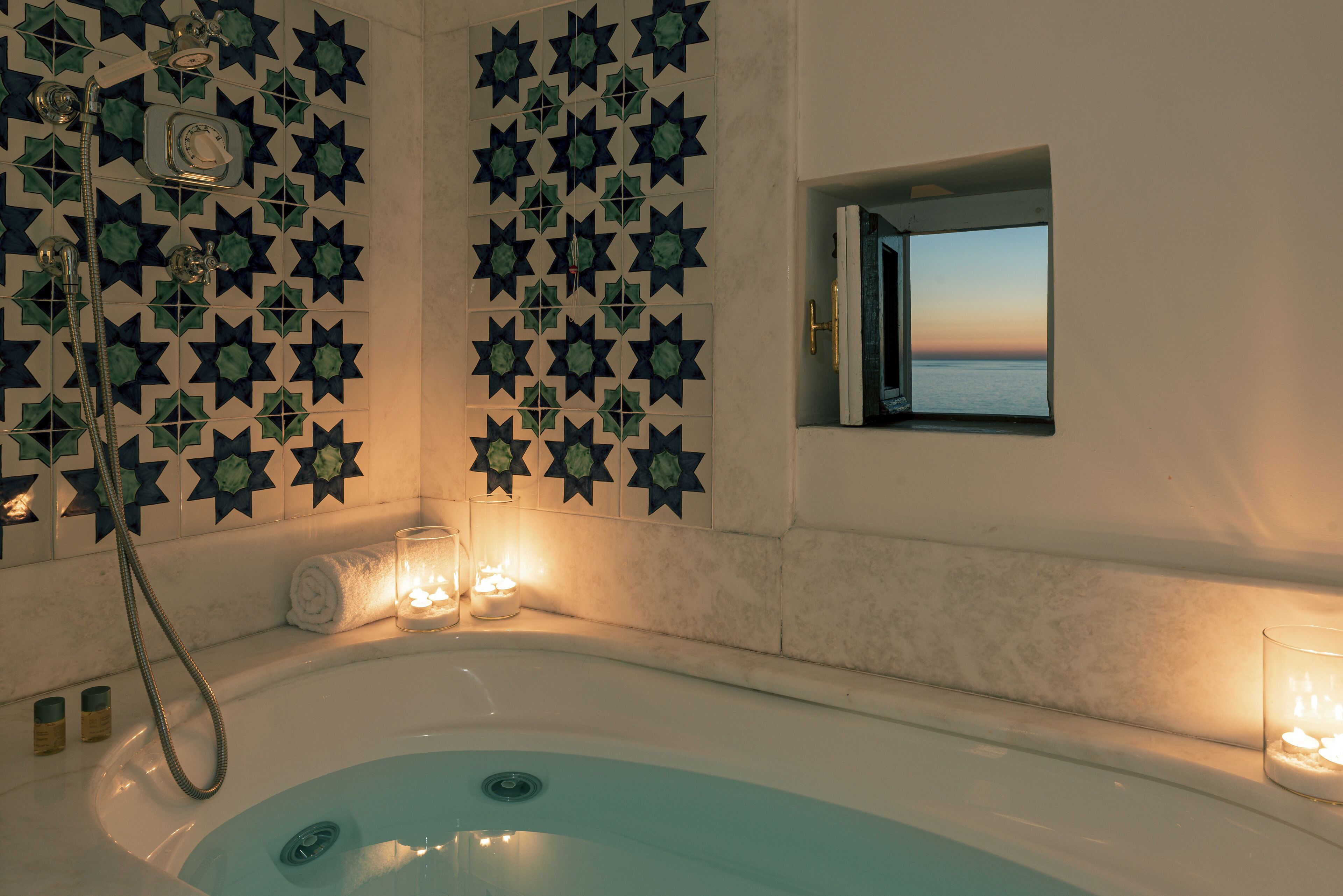 Une salle de bain avec une baignoire, une douche et une fenêtre donnant sur la mer.