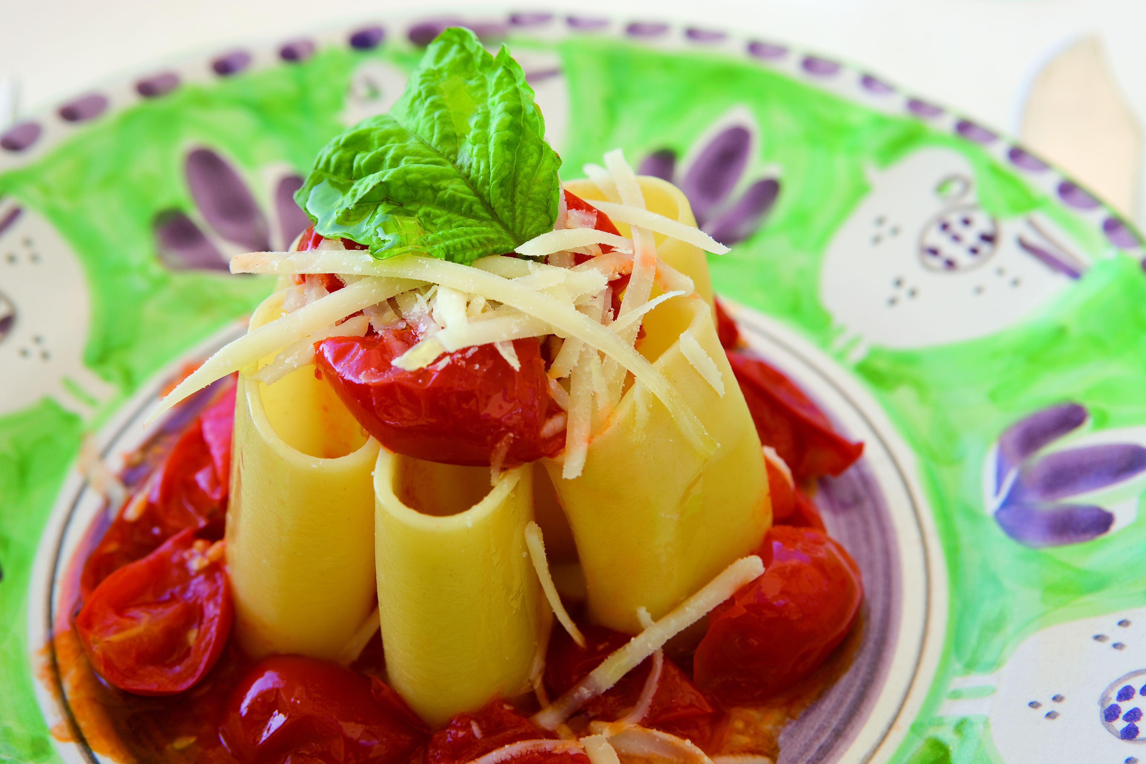 Un plato de pasta rellena con salsa de tomate y queso, decorado con una hoja de albahaca.