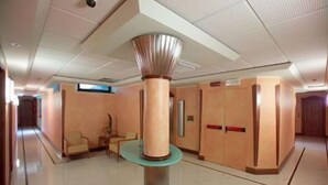 Un hall d’entrée spacieux avec une colonne centrale, un espace salon et des portes en bois.