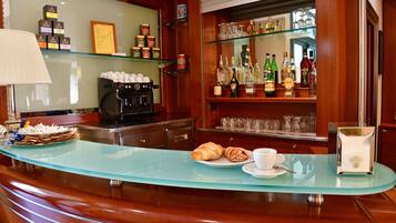 Angolo bar con bancone in vetro, pasticcini e una tazza di caffè.