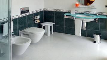 Un bagno moderno con box doccia in vetro, due servizi igienici, un lavandino e uno specchio.