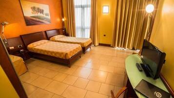 Una camera d'albergo con due letti, una scrivania con un portatile, una televisione e un quadro appeso al muro.
