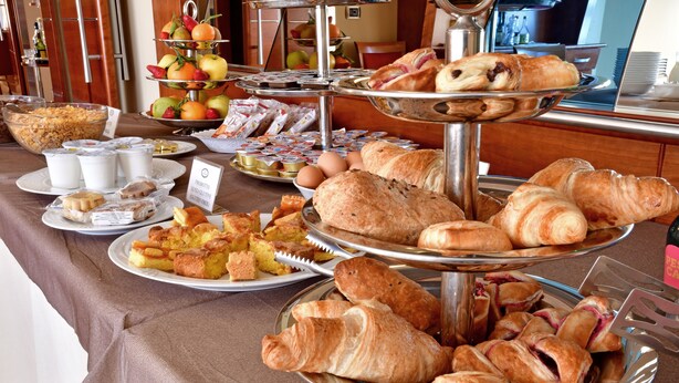 Un buffet proposant une variété de plats, notamment des pâtisseries, des fruits et des boissons.